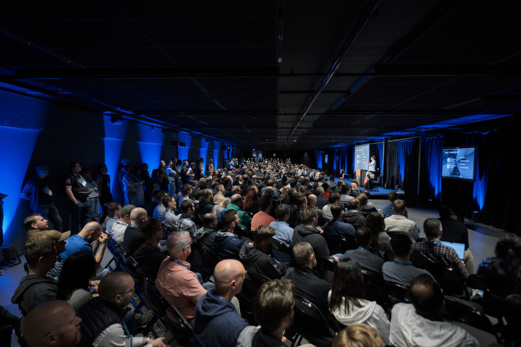 A large crowd of developers watching Adam Cogan present on stage